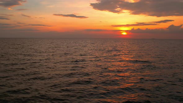 4K drone flying over the sea, sunset on the horizon.