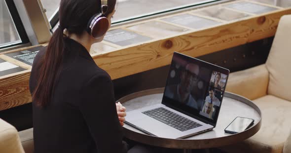 Back View of Young Caucasian Woman with Headphones During a Meeting Conference in a Public Bar