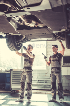 ome young auto mechanics in uniform repairing car