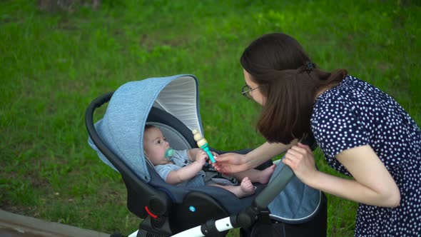 A Young Mother Shows a Rattle Toy to a Child