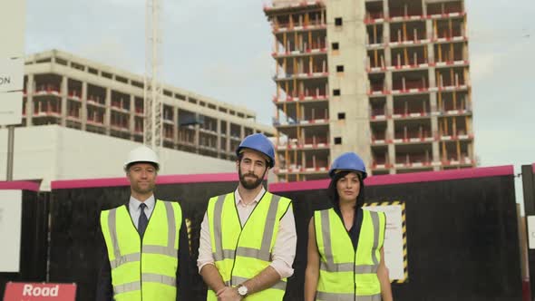 Men and woman looking at camera confidently at construction site