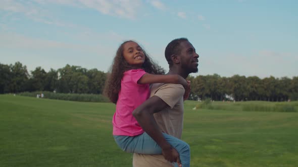 Joyful Dad Piggybacking Excited Daughter in Nature