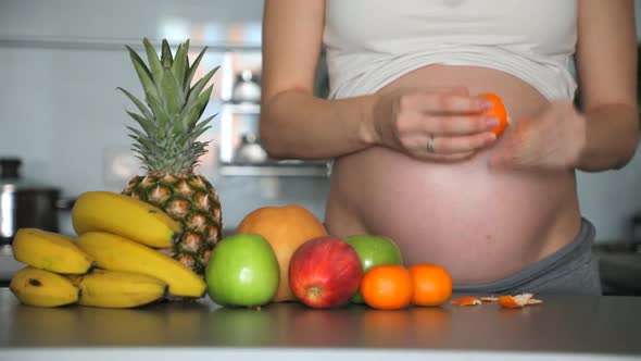 Pregnant Woman Peels and Eating a Tangerine in Home Kitchen with Different Fruits, Quick Speed Video