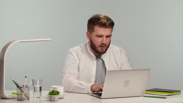 Young Man is Typing on the Computer Browsing the Web Looking at the Screen with Dislike and Disgust