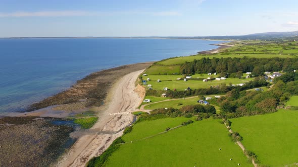 Aerial drone shot of Idyllic green farmland and fields on coast of Wales on sunny summer day with lo