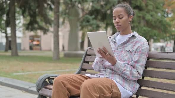 African Woman Using Tablet While Sitting Outdoor on Bench