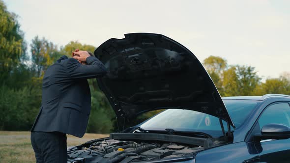 Rear View of a Man Examine Broken Car in Outdoor