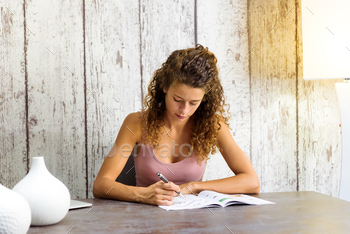 n a magazine or book concentrating on solving the clues seated at a table at home
