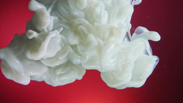 White Nacreous Paint in Water Against Red Background. alt