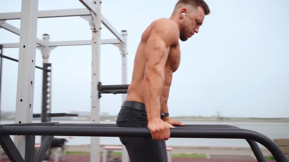 Muscular Man Naked Torso Doing an Exercise for Abdominal Muscles on Uneven Bars