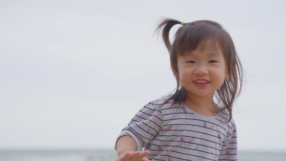Portrait of Asian little cute baby girl dancing on the beach enjoy family trip vacation at the sea.