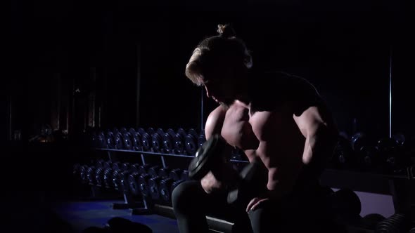 Handsome Power Athletic Man in Gym Sitting and Using Dumbbell