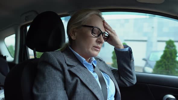 Woman Feeling Headache and Taking Medicine for Pain Relief Sitting in Car