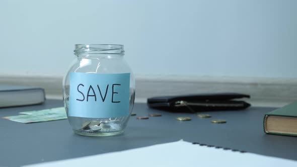 Coins falling into glass jar