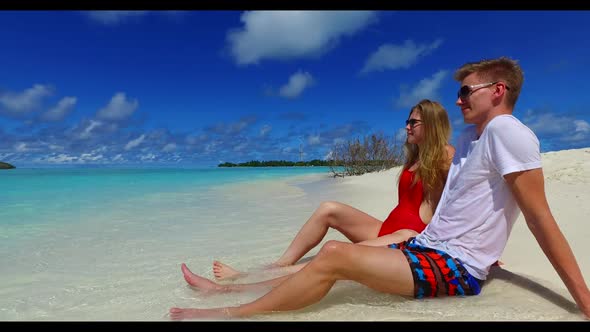 Man and woman posing on paradise tourist beach holiday by aqua blue lagoon and white sand background