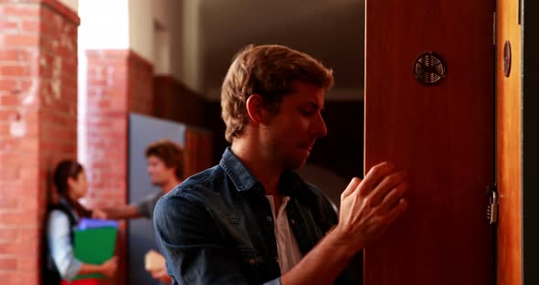 Depressed student walking to his locker and opening it