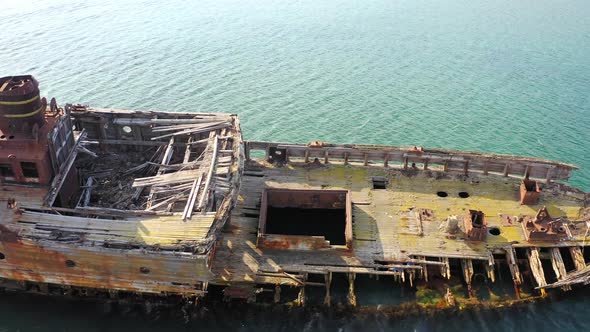 A Wrecked Wooden Ship Lies on the Seashore Covered with Rust