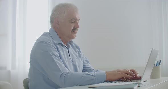 Adult Man Is Typing on Laptop Keyboard in His Office During Working Day, Sending Messages To