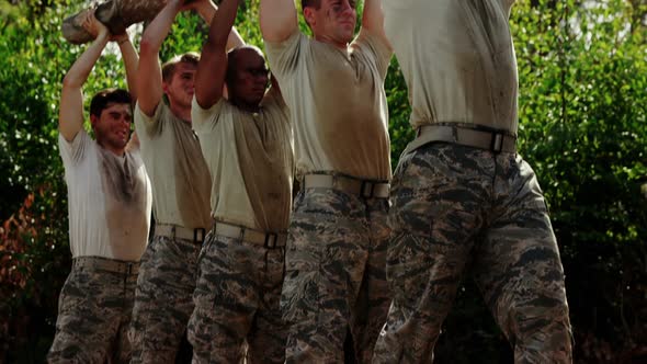 Military troops carrying heavy wooden log during obstacle course 