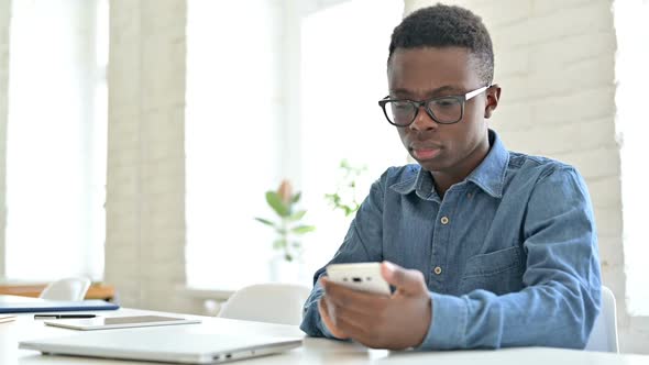 Upset Young African Man Reacting to Loss on Smartphone in Office