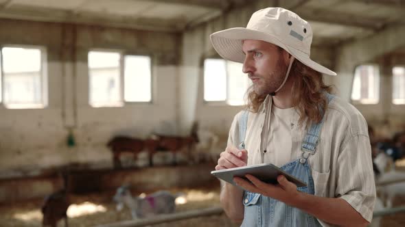 Male Owner of Goat Farm Working on Digital Tablet