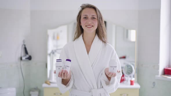 Portrait of Smiling Confident Slim Beautiful Woman Holding Bottles of Vitamin Supplements Smiling