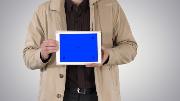 Male hands holding tablet with blue screen mockup on gradient