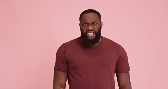 Young African American Man Get Mad Show Teeth on Pink Background