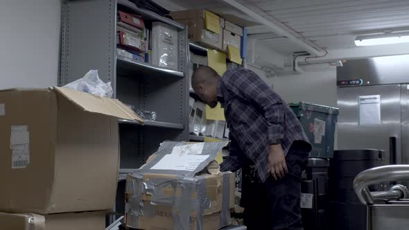 UK Indian Male Wearing Check Shirt Searching Different Shelves And Boxes In Office Basement. Locked