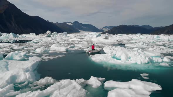 Aerial View of Male in Motorboat Sailing Between Icebergs by Alaskan Coastline. Glacier Melting, Cli