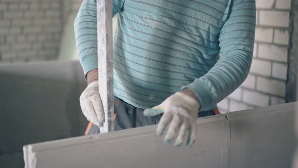 Man Holds Large Ruler and Measures Gypsum Plasterboard