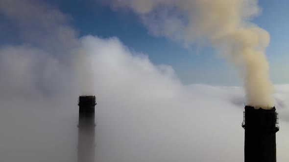 Coal Power Plant High Pipes with Black Smoke Moving Upwards Over Clouds Polluting Atmosphere