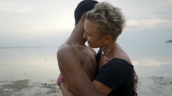 Interracial Couple with Age Differences Kissing and Hugging Each Other on Sunset Beach at Sunset