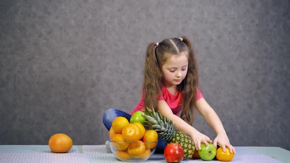 Little girl with fruit. Portrait of little girl sitting on table with fruit