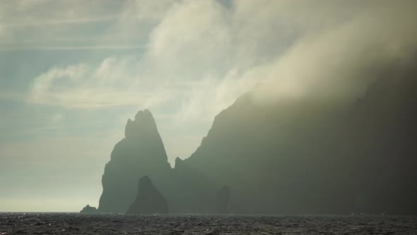 Mist Over the Sea with Rocky Volcanic Cliff is Lit By the Warm Sunset