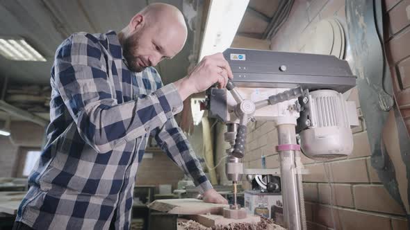 An Experienced Carpenter Works with a Drilling Machine in His Workshop