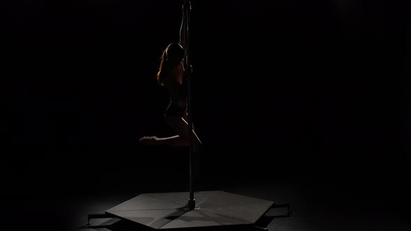 Woman with Sexy Shape Is Dancing Near the Pole . Black Background. Silhouette