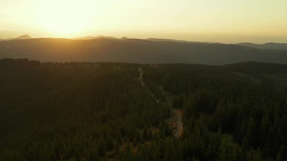 Drone Sunset in Mountain Forest View Against Bright Orange Sun at Golden Sky