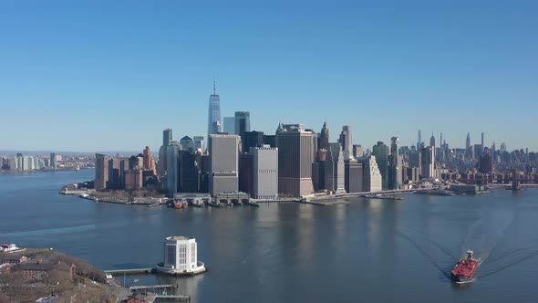 An aerial view of New York harbor on a sunny day with blue skies. The drone camera dolly in over the