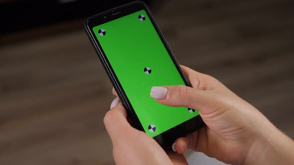 Closeup of Woman's Hand Browsing Smartphone with Green Screen at Home