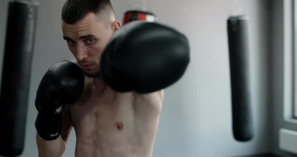 Kickboxer in Boxing Gloves Does Shadow Boxing and Trains at Boxing Club Fighter Man is Fighting with