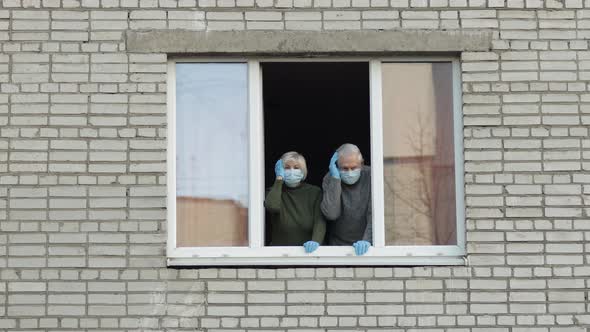 Old Grandparents Stay at Window Isolated at Home on Quarantine. Coronavirus