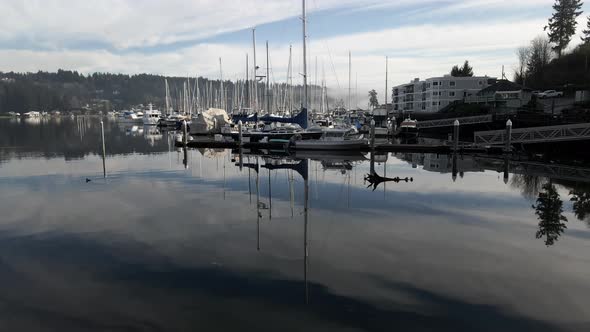 Glass-like water reflecting the sky and Fog shrouded Mount Rainier over Gig Harbor, aerial track up