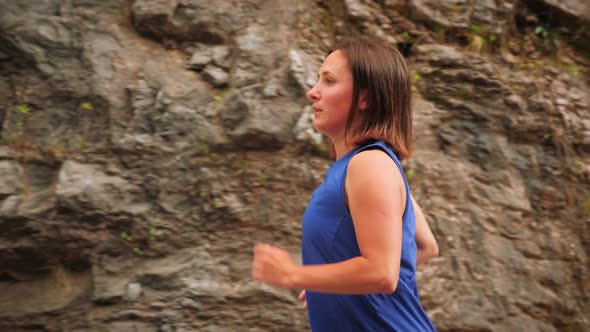 Running concept. Energetic young woman running alone on mountain road