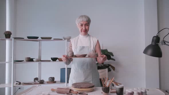 Asian elderly woman enjoying pottery work at home.