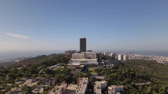 Tall building on green hills with trees in the background Haifa city with sea and harbor, Israel