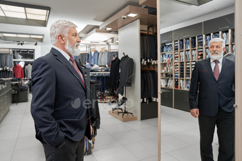 oking at mirror and estimating new outfit. Fashionable male client choosing and buying clothes in boutique. Concept of elegance and fitting.