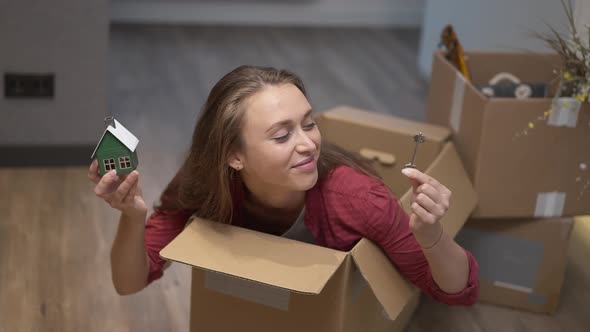 Cheerful Millennial Caucasian Woman with Toothy Smile Having Fun Sitting in Cardboard Box Showing