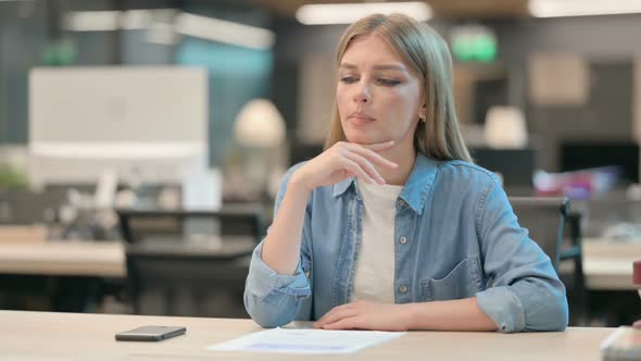 Pensive Young Woman Sitting in Office Thinking