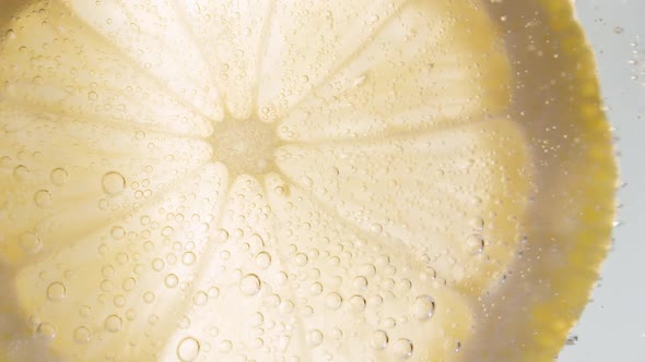 Slow Motion Macro Shot of a Lemon Slice in Water Bubbles Drinking Cold Lemonade